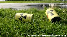 Model nuclear waste canisters lie on the grass near a road