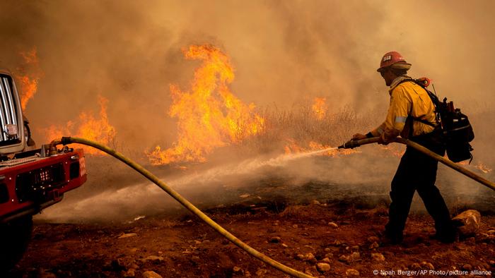 Un pompier pulvérise de l'eau tout en essayant d'empêcher l'incendie d'Electra de se propager dans la communauté de Pine Acres dans le comté d'Amador