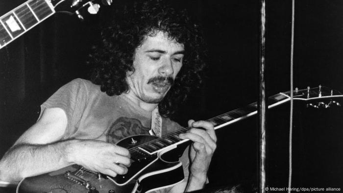 Carlos Santana toca la guitarra, en una foto de 1971, en blanco y negro.