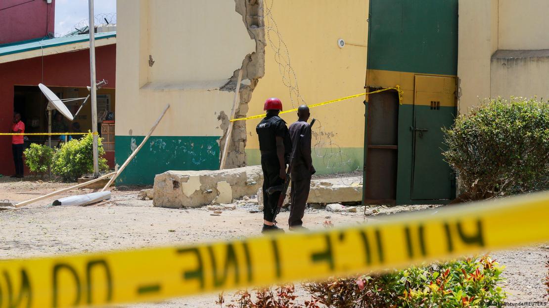 Police stand by a damaged prison building near Abuja with police tape in the foreground Police stand by a damaged prison building near Abuja with police tape in the foreground