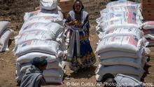 FILE - An Ethiopian woman stands by sacks of wheat to be distributed by the Relief Society of Tigray in the town of Agula, in the Tigray region of northern Ethiopia Saturday, May 8, 2021. World hunger rose in 2021 with around 2.3 billion people facing moderate or severe difficulty obtaining food -- and that was before the Ukraine war which has sparked increases in the cost of grain, fertilizer and energy, according to a U.N. report launched Wednesday, July 6, 2022. (AP Photo/Ben Curtis, File)