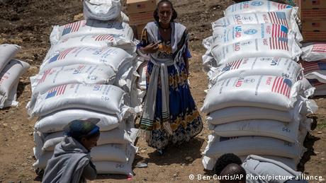 A woman stands between sacks of wheat in Agula, Tigray region, Ethiopia