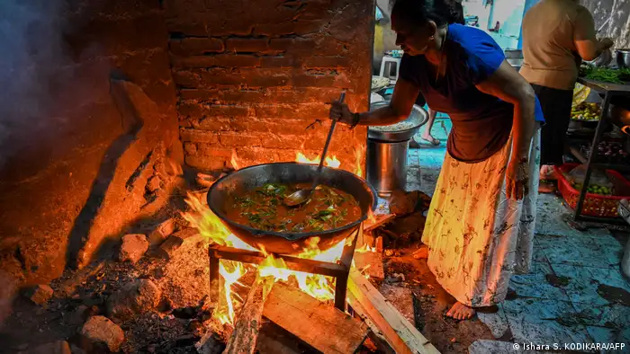 A woman uses firewood to cook a meal at a hotel in Colombo. 