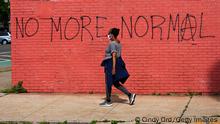 NEW YORK, NEW YORK - MAY 25: A woman wearing a protective mask walks past graffiti that reads 'NO MORE NORMAL' during the coronavirus pandemic on May 25, 2020 in the Queens borough of New York City. Government guidelines encourage wearing a mask in public with strong social distancing in effect as all 50 states in the USA have begun a gradual process to slowly reopen after weeks of stay-at-home measures to slow the spread of COVID-19. (Photo by Cindy Ord/Getty Images)