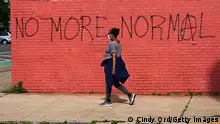 NEW YORK, NEW YORK - MAY 25: A woman wearing a protective mask walks past graffiti that reads 'NO MORE NORMAL' during the coronavirus pandemic on May 25, 2020 in the Queens borough of New York City. Government guidelines encourage wearing a mask in public with strong social distancing in effect as all 50 states in the USA have begun a gradual process to slowly reopen after weeks of stay-at-home measures to slow the spread of COVID-19. (Photo by Cindy Ord/Getty Images)