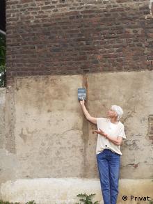 Marietta Thien zeigt an einer Wand, wie hoch das Wasser stand