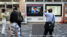 People look at a television broadcasting the news about the attack on former Japanese prime minister Shinzo Abe earlier in the day, along a street of Tokyo on July 8, 2022. - Shinzo Abe was shot at a campaign event in the city of Nara on July 8, a government spokesman said, as local media reported the nation's longest-serving premier was showing no vital signs. (Photo by Charly TRIBALLEAU / AFP) (Photo by CHARLY TRIBALLEAU/AFP via Getty Images)