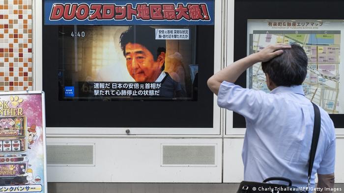 Man looks at TV news about attack on Shinzo Abe on a street in Tokyo on July 8, 2022