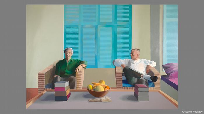 Das Gemälde Christopher Isherwood and Don Bachardy von David Hockney zeigt zwei Männer, die in Sesseln vor einem Tisch mit Büchern und Obstschale nebeneinander sitzen. 