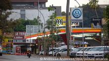 Das Logo des Autobauers Volkswagen (VW) ist neben einer Tankstelle am Rande einer Straße zu sehen.