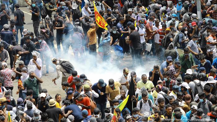 A group of protesters react as a tear gas shell lands in their midst in Colombo.