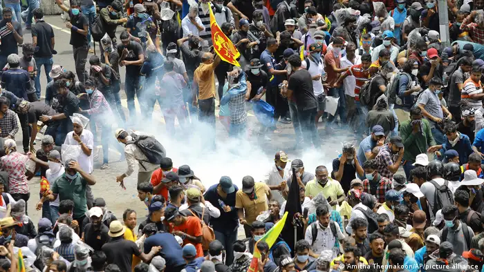 A group of protesters react as a tear gas shell lands in their midst in Colombo.