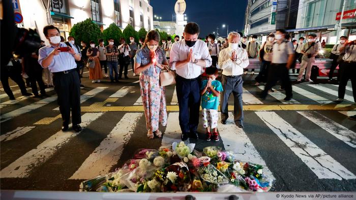  People pray at a makeshift memorial at the scene where the former Prime Minister Shinzo Abe was shot while delivering his speech to support the Liberal Democratic Party's candidate during an election campaign in Nara, Friday, July 8, 2022