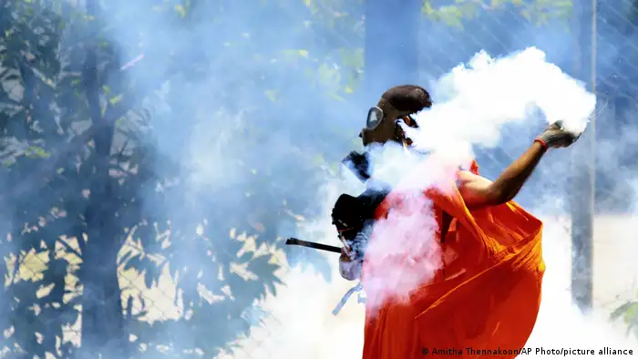 A man throws back a tear gas canister after it was fired by police to disperse protesters in Colombo, Sri Lanka,