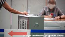 Ein Wähler gibt bei den Oberhauswahlen seine Stimme ab, während Vertreter einer lokalen Wahlkommission in einem Wahllokal zusehen. +++ dpa-Bildfunk +++