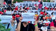 Demonstrators hold up signs during a protest over the freezing of deposits by some rural-based banks, outside a People's Bank of China building in Zhengzhou, Henan province, China July 10, 2022, in this screengrab from video obtained by Reuters. Text in foreground reads, Henan Bank, return to us our legal deposits! The people's life-saving deposits! Reuters TV via REUTERS ATTENTION EDITORS - THIS IMAGE HAS BEEN SUPPLIED BY A THIRD PARTY.