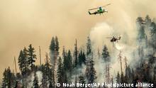 Seen from unincorporated Mariposa County, Calif., a helicopter drops water on the Washburn Fire burning in Yosemite National Park on Saturday, July 9, 2022. (AP Photo/Noah Berger)