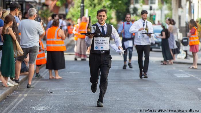 Un camarero corre con una botella de champaña en la Carrera de camareros, en el distrito de Soho, Londres.