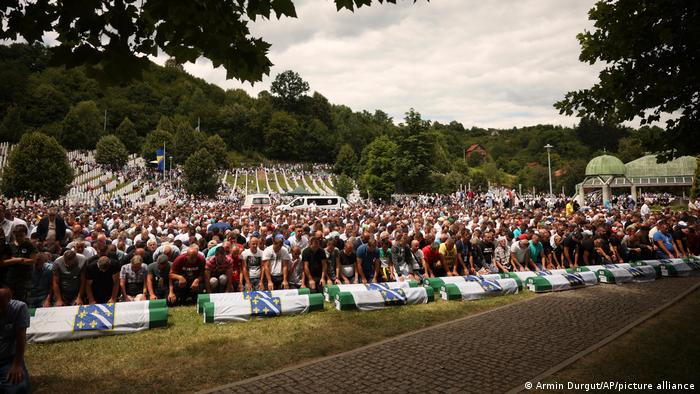 Bosnian muslim men pray next to the coffins containing the remains of 50 newly identified victims of Srebrenica Genocide 