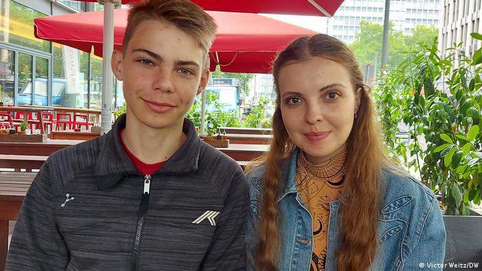 Anastasia (r) a young woman with long hair and a jeans jacket, and her younger brother Artyom (i), weraing shortish hair and a gray fleece jacket, sit at an outdoor cafe in Cologne, Germany
