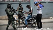 11.07.2022****Armed forces check two men who were riding a motorcycle for weapons, at the area of ​​state offices of Port-au-Prince, Haiti, Monday, July 11, 2022. Radio TV Caraibe, a popular radio station in Haiti announced on Monday that it would stop broadcasting for one week to protest widespread violence in the capital. (AP Photo/Odelyn Joseph)