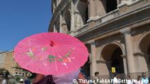 A tourists holds a paper umbrella to protect herself from the sun near the Colosseum on June 21, 2017 in Rome. In Italy, forecasters say the current heatwave could turn out to be the most intense in 15 years, with temperatures around eight degrees above the seasonal average -- 39 degrees Celsius in Milan and up to 30 in the Alps at an altitude of 1,000 metres (3,300 feet). (Photo by Tiziana FABI / AFP) (Photo credit should read TIZIANA FABI/AFP via Getty Images)