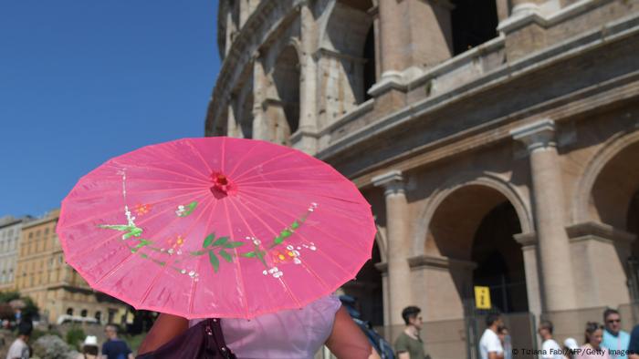 A woman carries an umbrella in sunny Rome