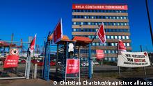 14.07.202, Hamburg - Schilder mit der Aufschrift «Heute Warnstreik!» und Flaggen mit dem Verdi-Logo sind an einem Eingang zum Container Terminal Burchardkai (CTA) der HHLA (Hamburger Hafen und Logistik AG) befestigt. Im Konflikt um die Entlohnung der Hafenarbeiter an den großen deutschen Nordseehäfen ist weiterhin keine Einigung in Sicht. Die Gewerkschaft Verdi hat die Beschäftigten der Seehäfen zu einem 48-stündigen Warnstreik aufgefordert. 