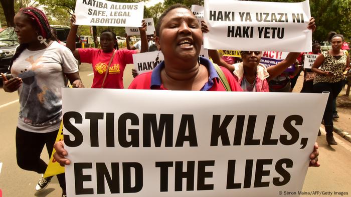 An activist holds up a placard reading 'Stigma kills, end the lies' during a demonstration outside the City County Assembly in Nairobi