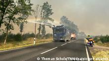 Ein Wasserwerfer der Polizei ist in einem Waldstück bei einem Waldbrand im Einsatz. Die vom Waldbrand in Treuenbrietzen nahe Berlin betroffene Fläche hat sich in der Nacht zum Sonntag ausgedehnt.