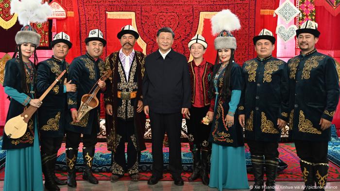 In this photo released by China's Xinhua News Agency, Chinese President Xi Jinping, center, poses for a photo with performers of the Manas, a cultural epic of the Kyrgyz people