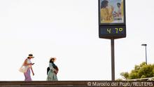 FILE PHOTO: Women walk next to a thermometer displaying 47 Celsius (116.6 Fahrenheit) during the first heatwave of the year in Seville, Spain June 11, 2022. REUTERS/Marcelo del Pozo/File Photo
