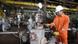 Smiling Libyan oil worker in orange overalls and a white helmet stands at a pipeline valve Smiling Libyan oil worker in orange overalls and a white helmet stands at a pipeline valve