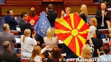 North Macedonian members of Parliament from the ruling SDSM party, hold European Union and North Macedonian flags, during a parliamentary debate on a French-brokered deal aimed at settling disputes with Bulgaria and clearing the way to EU membership, in Skopje, North Macedonia, July 16, 2022. REUTERS/Ognen Teofilovski