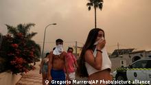 Residents protect themselves from the smoke as a wildfire advances near a residential area in Alhaurin de la Torre, Malaga, Spain, Saturday, July 16, 2022. Wildfires continue to spread across Spain as firefighters work to bring them under control. (AP Photo/Gregorio Marrero)