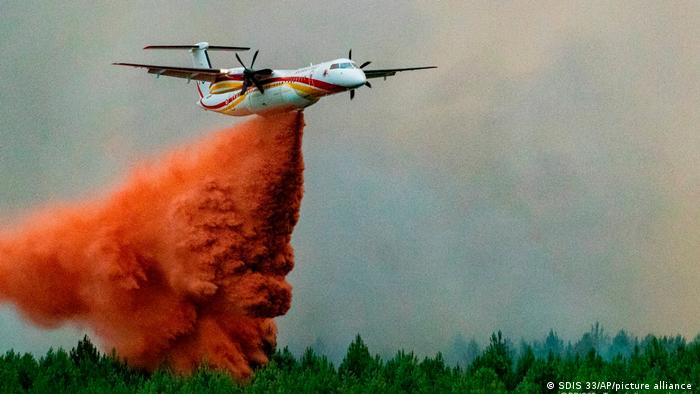 A water-bombing plane flying over a burning forest