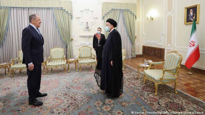 Russian Foreign Minister Sergey Lavrov (l) and Iranian President Ebrahim Raisi (r) stand together in an ornate room in Tehran, Iran