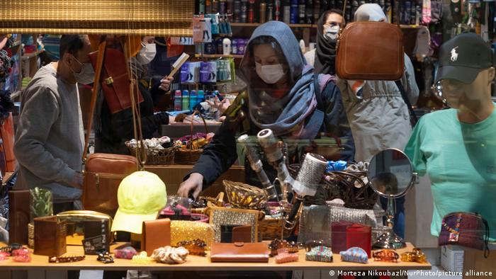 A woman with a blue headscarf alongside other customers in a luxury goods shop in Tehran, Iran