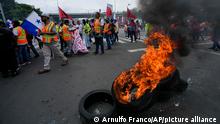 Construction workers burn tires as they protest in support of striking teachers, outside the National Assembly in Panama City, Wednesday, July 13, 2022. Panamanians have taken to the streets in protest for more than a week, building upon anger over fuel prices that have nearly doubled to make known their general dissatisfaction with the government of President Laurentino Cortizo. (AP Photo/Arnulfo Franco)