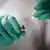 Mãos enluvadas enchem seringa com conteúdo de ampola
