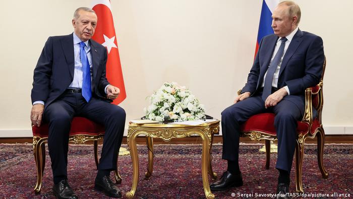 Der russische Präsident Wladimir Putin und der türkische Präsident Recep Tayyip Erdogan sitzen getrennt durch einen kleinen Tisch auf mit rotem Samt bezogenen Stühlen