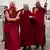 The Dalai Lama arrives at the airport in Leh, Ladakh, India, supported by two men and wearing scarlet and yellow robes
