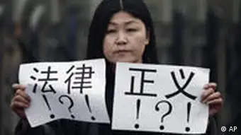 An activist holds papers bearing the words law and justice outside a court house during the trial of Zhao Lianhai in Beijing, Tuesday, March 30, 2010. Zhao Lianhai, who organized a support group for parents of children sickened in one of China's worst food safety scandals pleaded not guilty Tuesday to charges of inciting social disorder, his lawyer said. (AP Photo/Andy Wong)