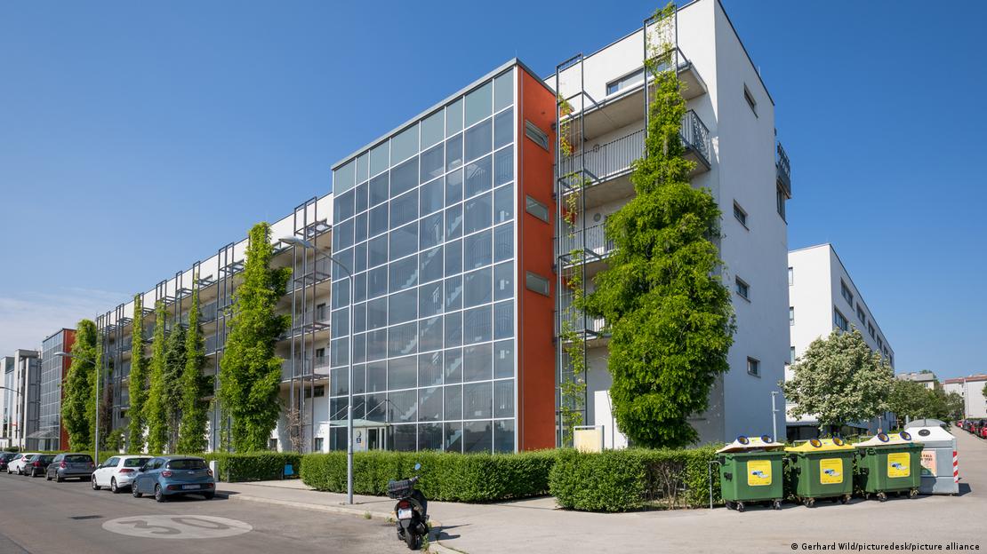 Viyana'da dış cephesi yeşil bitkilerle kaplanmış çok katlı bir konut binası, önündeki cadde ve park halindeki araçlarla birlikte görülüyor