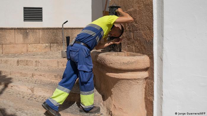 A street sweeper man cools off with water at a fountain in Ronda in Spain. 