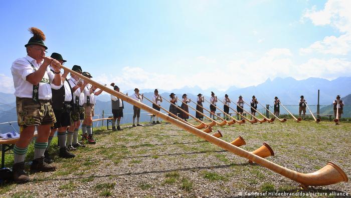 Frauen und Männer der Alphorngruppe EUREGIO via salina spielen bei der 30. Berglar-Kirbe vor dem Alpen-Panorama
