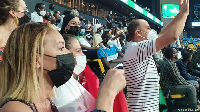 Woman wearing a face mask in a stadium, surrounded by other spectators