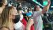Woman wearing a face mask in a stadium, surrounded by other spectators Woman wearing a face mask in a stadium, surrounded by other spectators