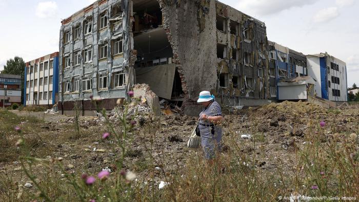 Foto de una persona que camina frente a una escuela dañada en la región de Donetsk.