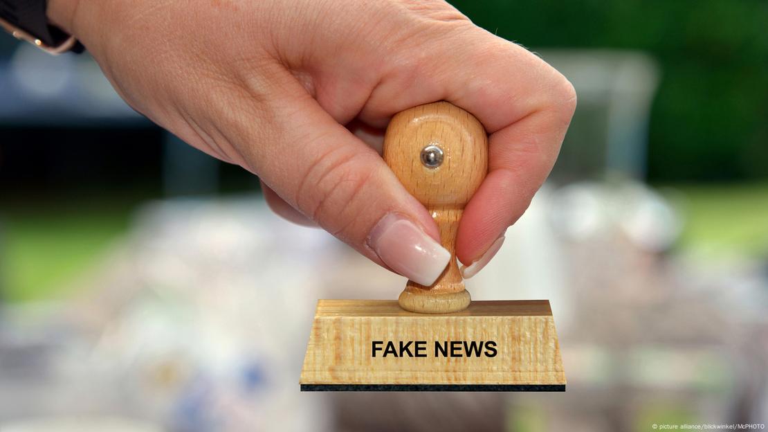 Foto simbólica de una mano que sostiene un sello que dice "Fake News"